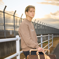 トップス¥178,200、パンツ¥192,500、スニーカー¥169,400、サングラス¥81,400、チェーンベルト¥148,500、ピアス(単品) ¥51,700、リング¥61,600、ウォッチ｢タンブール オトマティック スティール ブルー｣¥3,179,000、バッグ｢キーポル·バンドリエール 45｣¥414,700、スーツケース｢ホライゾン 55｣¥507,100、ウォレット｢ポルトフォイユ·ブラザ｣¥105,600／PHOTO CREDIT：LOUIS VUITTON