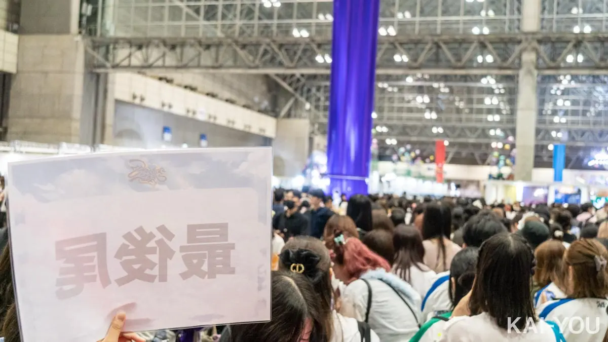 佐伯イッテツさんのパネル撮影待機列最後尾から。奥の紫色の垂れ幕の下にパネルが設置されている。