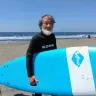 サーフボードを持つ五頭岳夫さん